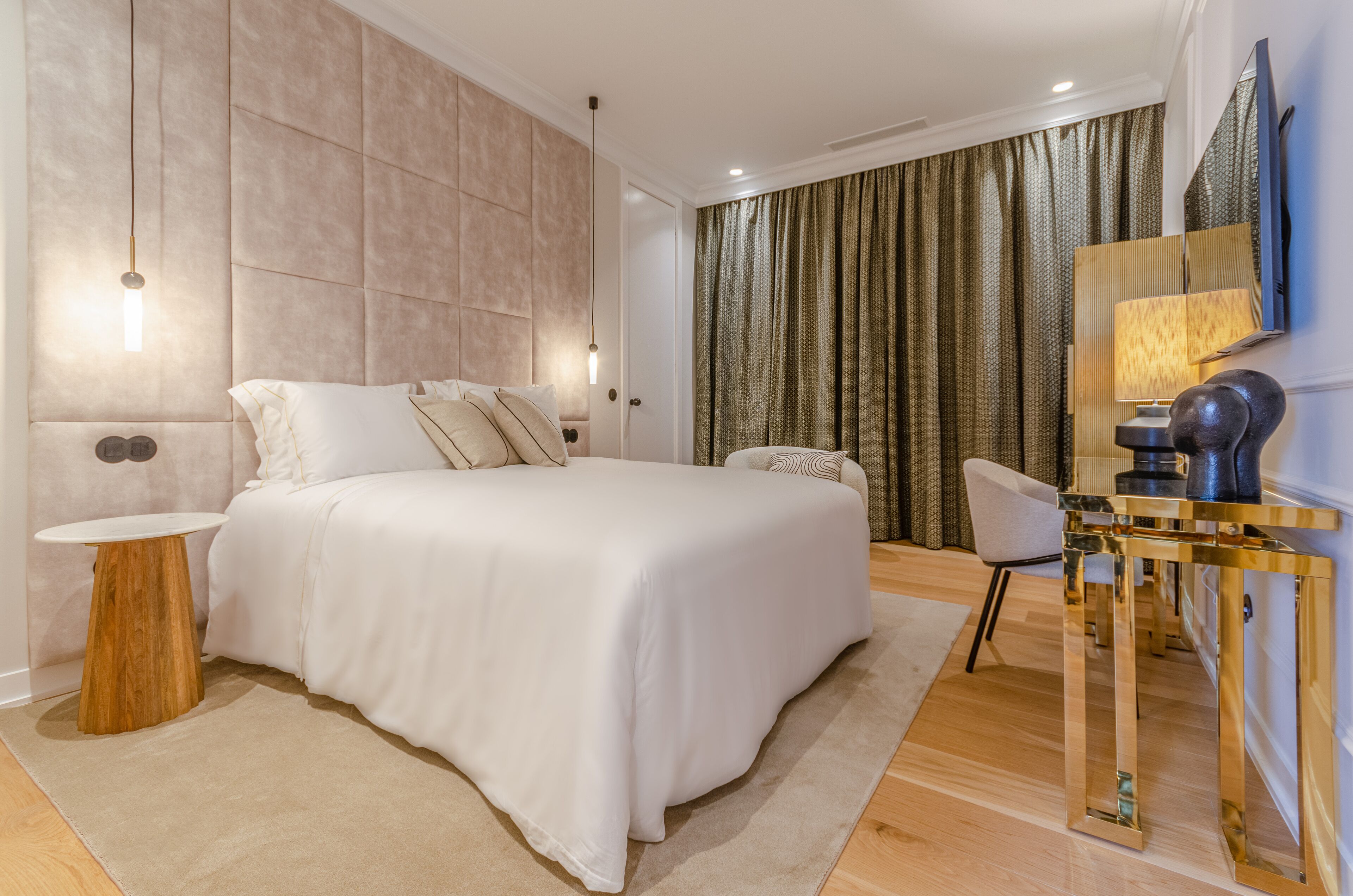 A modern bedroom with a large bed, a bedside table, a chair, a TV, and a lamp.