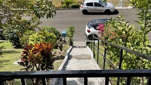 A view of a coastal area with boats in the water, a white car parked in a driveway, and a building with red roofs. - Maison Bel bonjou (Le Marin)