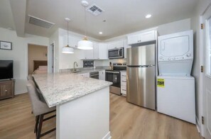 A modern kitchen with white cabinets, stainless steel appliances, and a granite countertop. - Gorgeous Guest House with Big Yard (Tucson)