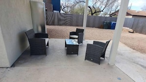Un'area patio all'aperto con mobili in vimini e pavimento in cemento.