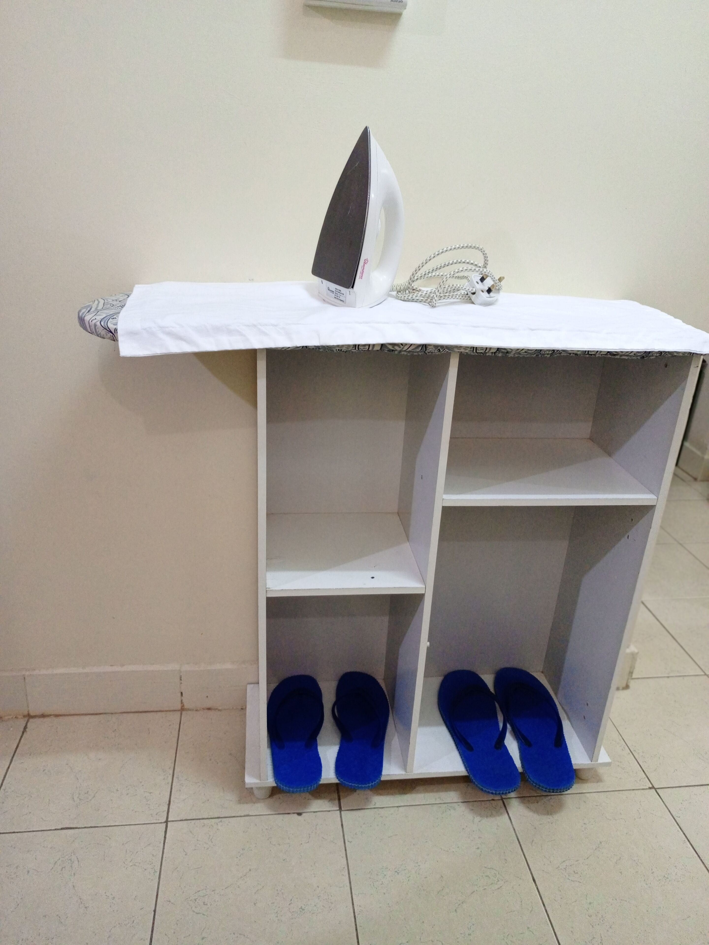 A white shelf with a pair of blue slippers on it.