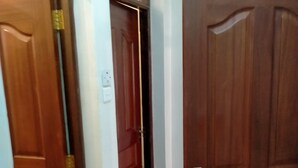 A hallway with wooden doors, a tiled floor, and a light switch on the wall. - MILANY HOMES - NEAR JKIA AIRPORT (Syokimau)