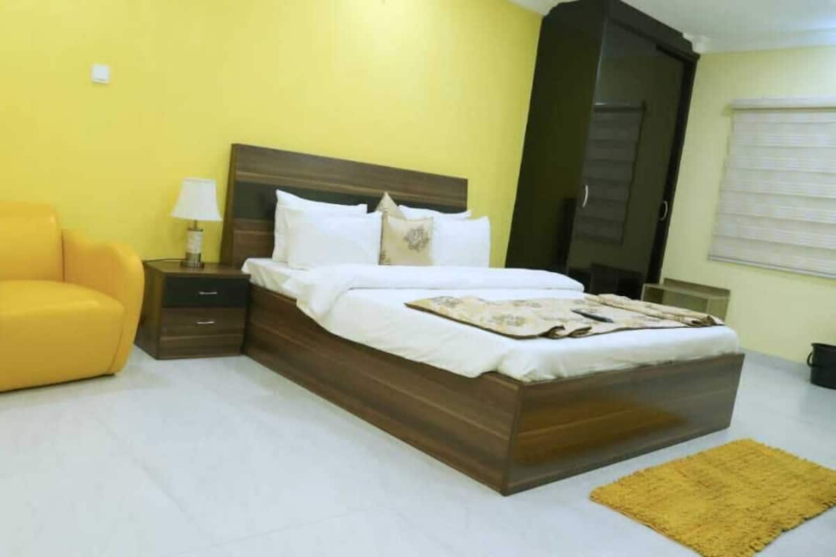 A bedroom with a bed, a chair, a nightstand, and a wardrobe.