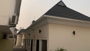 Un edificio residencial con techo oscuro, paredes color beige y un buzón negro pequeño.
