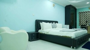 Un dormitorio con cama, mesitas de noche, una silla y un armario.