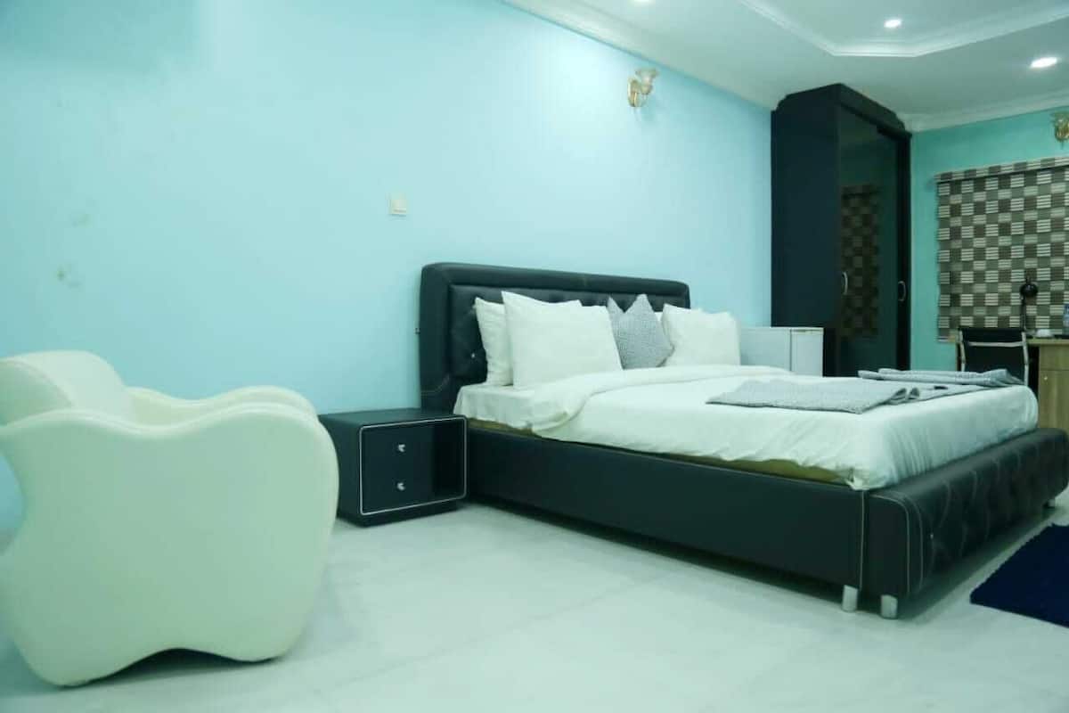 A bedroom with a bed, bedside tables, a chair, and a wardrobe.