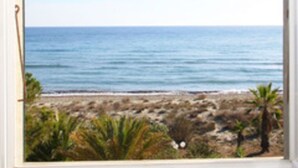Ein Fenster mit Blick auf Strand und Meer.