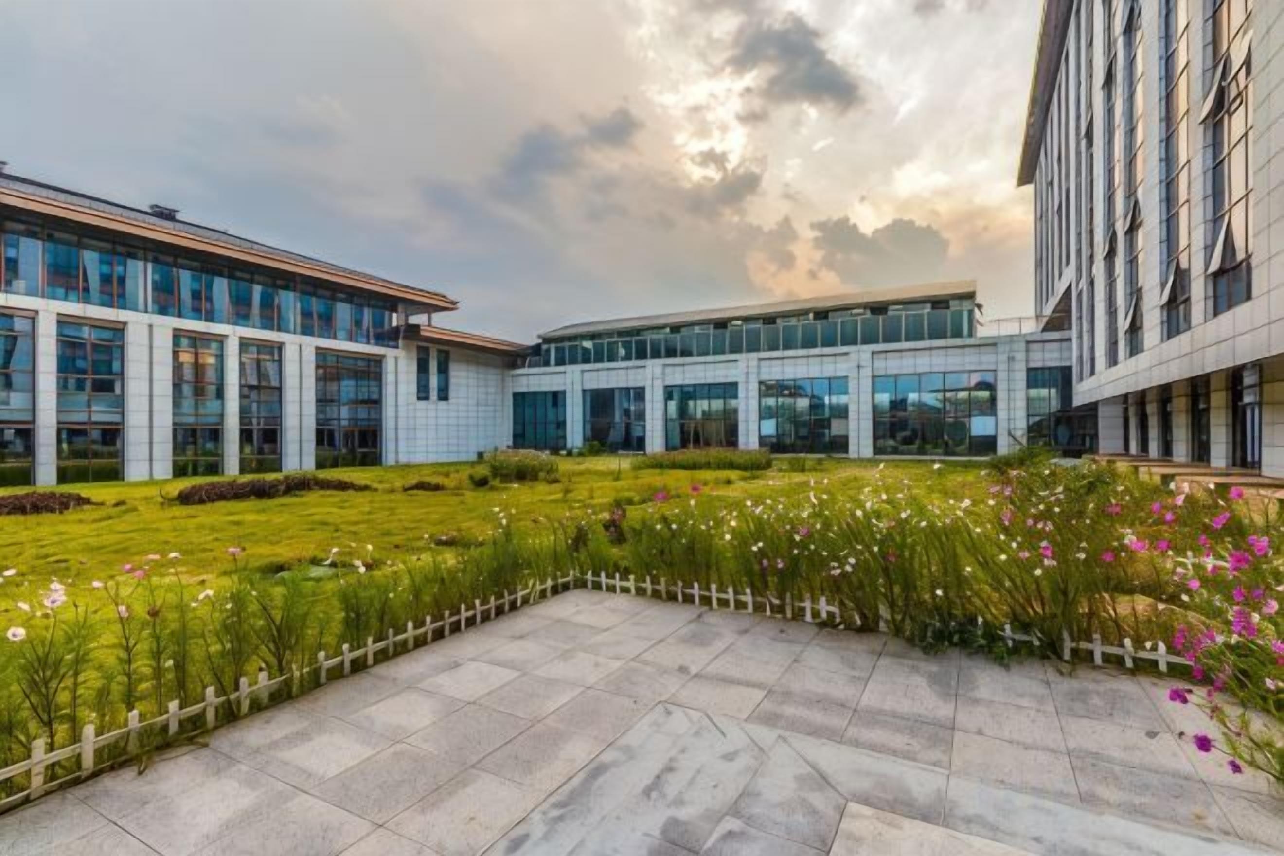 A modern building with a courtyard featuring a garden and a paved walkway.