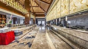 A spacious hotel lobby with a high ceiling, marble flooring, and a central reception desk. - Dahua Jianguo Hotel (Zhuolu)