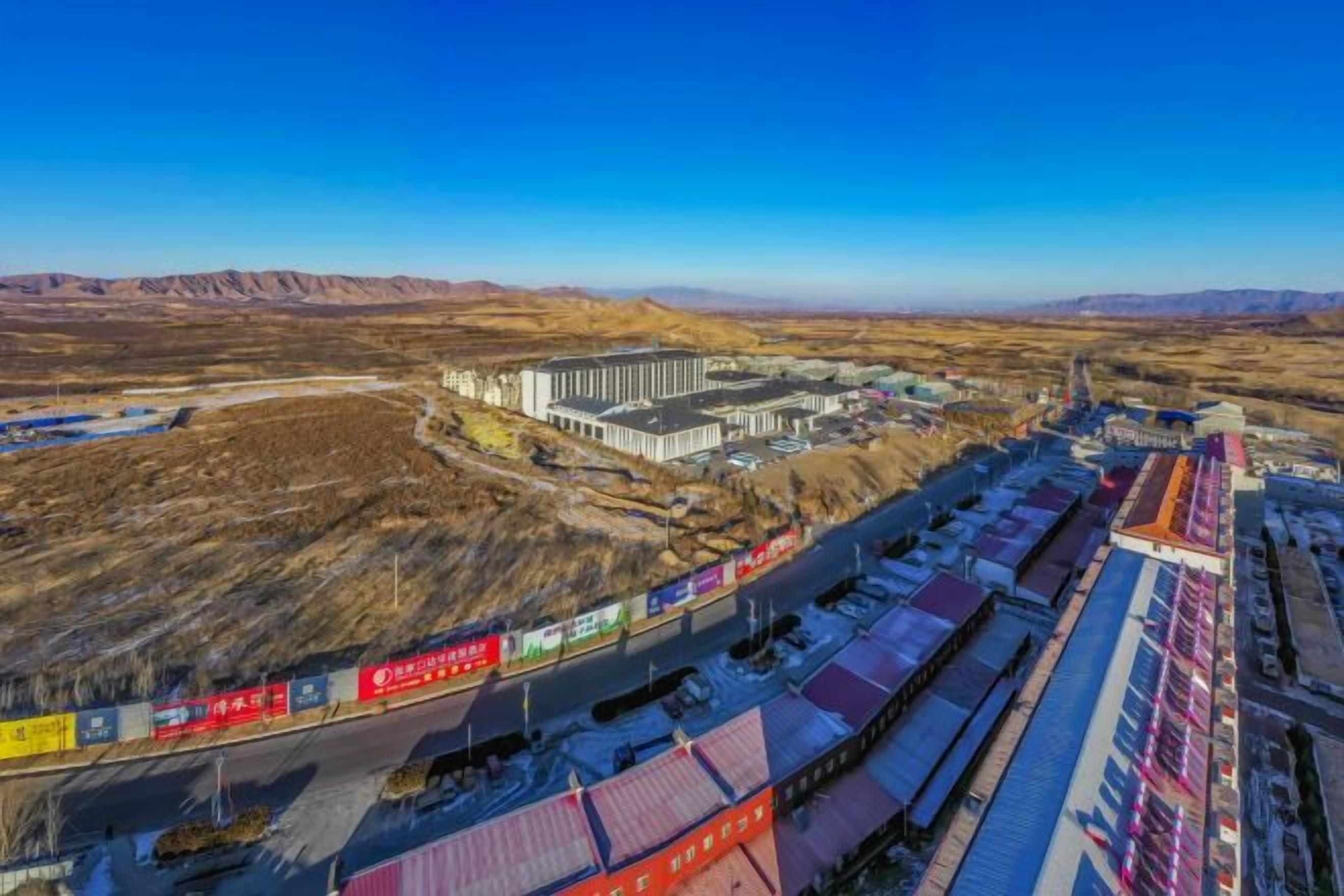 A large industrial complex with multiple buildings and a long train track.
