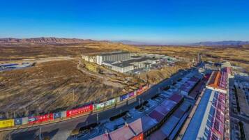 A large industrial complex with multiple buildings and a long train track.