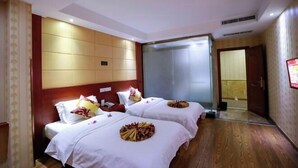Une chambre d’hôtel avec deux lits, un grand miroir et un plancher en bois.