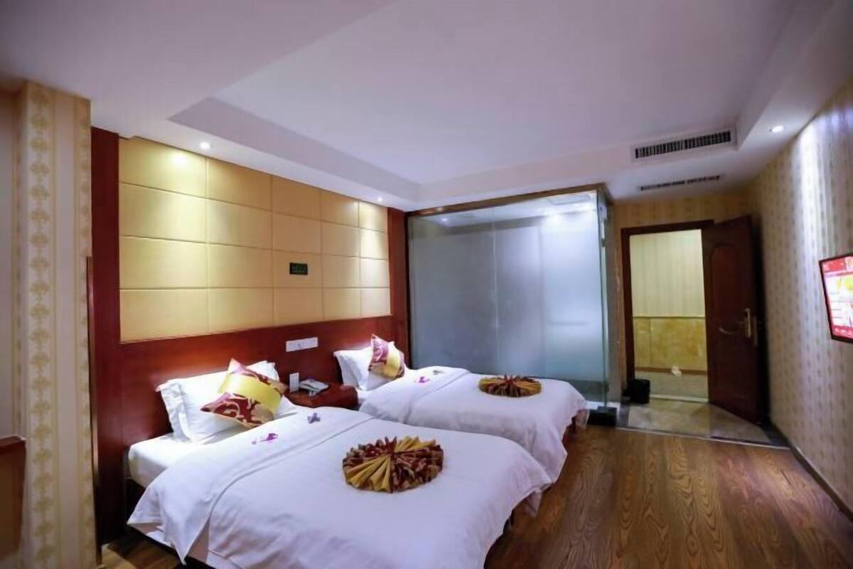 A hotel room with two beds, a large mirror, and a wooden floor.