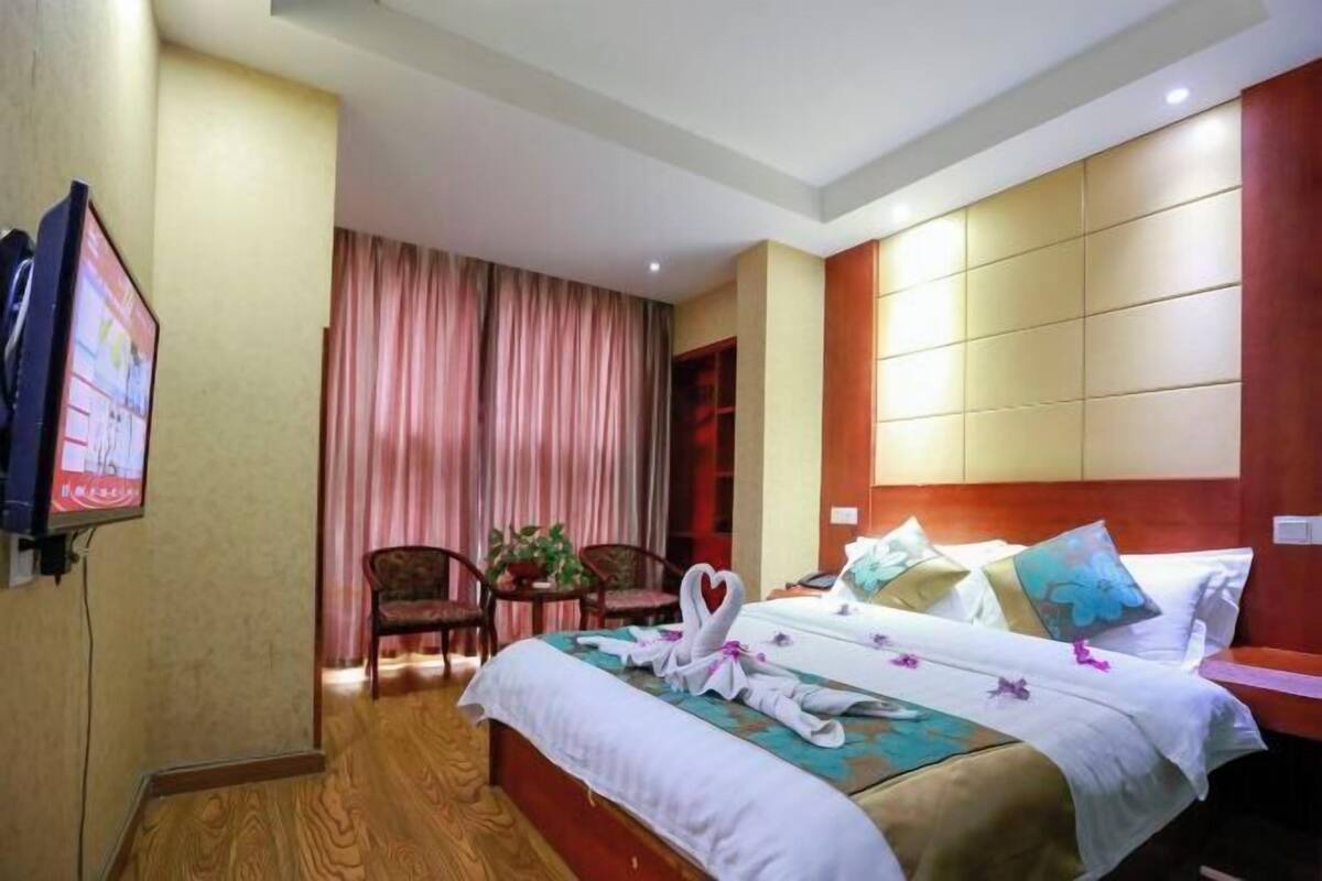 A hotel room with a bed, a TV, a desk, and a chair.
