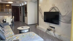 Un salon moderne avec un canapé, une table basse et un téléviseur à écran plat fixé au mur.