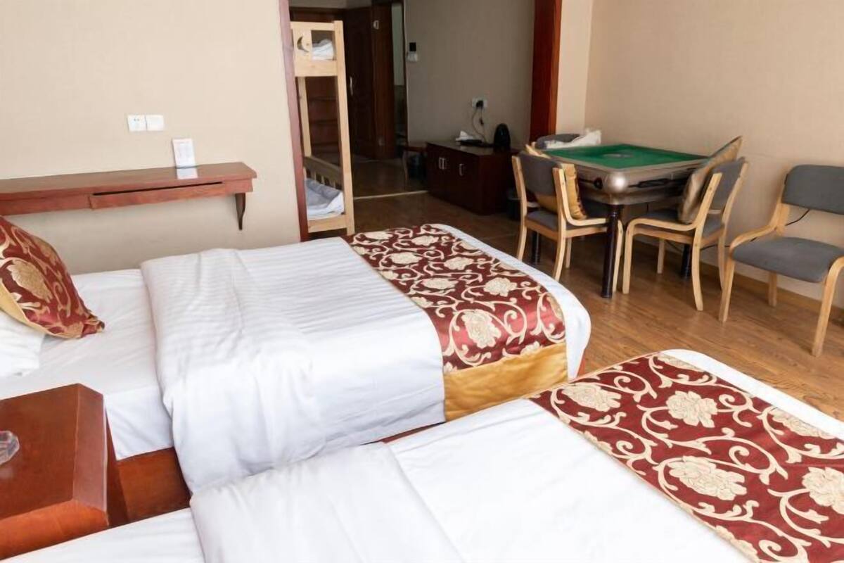 A hotel room with two beds, a desk with a green pool table, and a chair.
