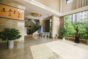 A hotel lobby with a marble floor, a staircase, a reception desk, and potted plants. - Dijing Express Hotel (Qingyang)