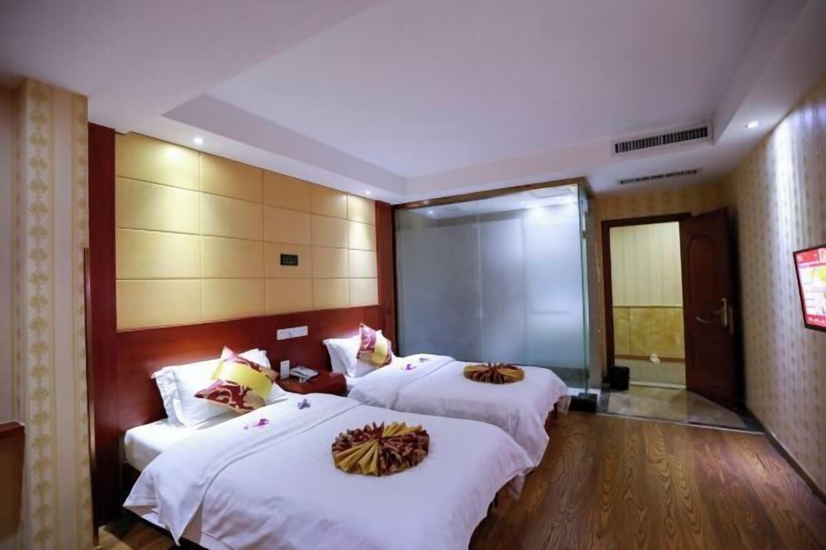 A hotel room with two beds, a large mirror, and a wooden floor.