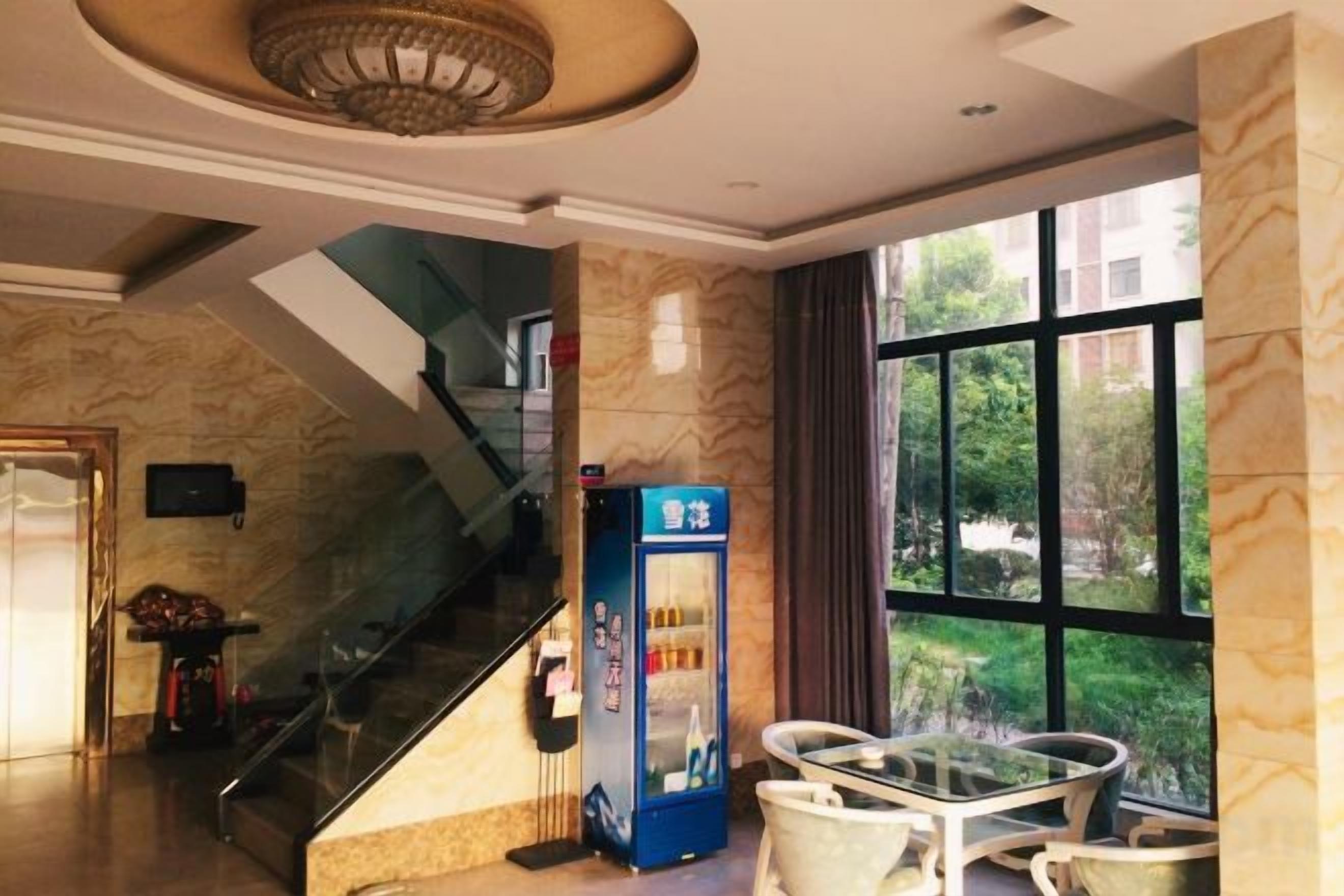 Eine Hotelhalle mit einer Marmortreppe, einem Automaten und einem Glastisch mit Stühlen.
