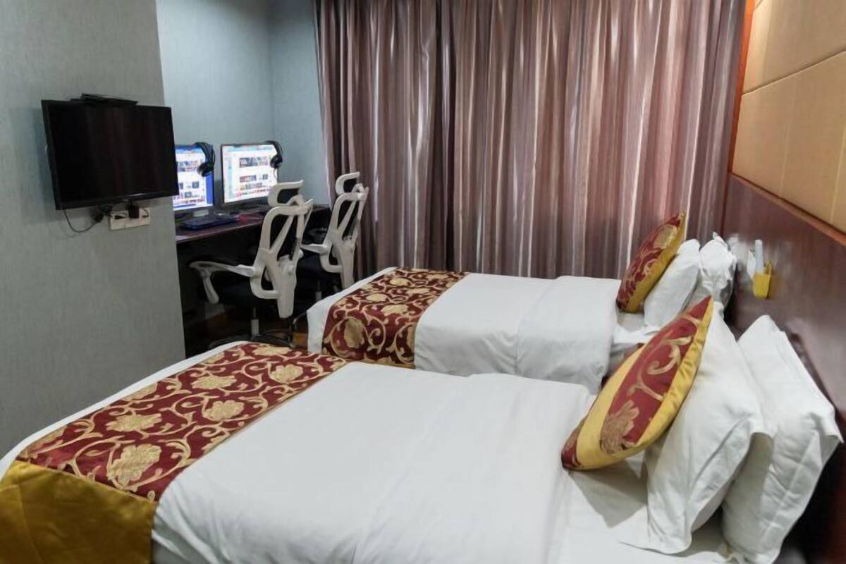 A hotel room with two beds, a desk with a computer, and a TV.