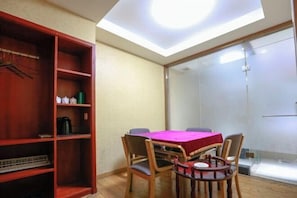 A room with a skylight, a table with a red tablecloth, wooden chairs, and a bookshelf with various items. - Dijing Express Hotel (Qingyang)