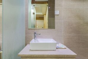 A bathroom with a white sink, a mirror, and a shower visible in the background. - Dijing Express Hotel (Qingyang)