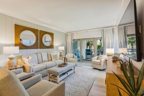 A modern living room with a sofa set, two side tables with lamps, a coffee table, and a television.