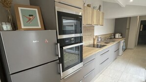 A modern kitchen with stainless steel appliances, a wooden countertop, and a tiled floor.