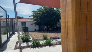 A courtyard with a wooden pergola, a tiled patio, and a garden with various plants and flowers.