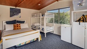 A bunk bed with a desk and a wardrobe in a room with a wooden ceiling and a window. - Kon Tiki Retreat - Whiritoa Beach Holiday Home (Whiritoa)