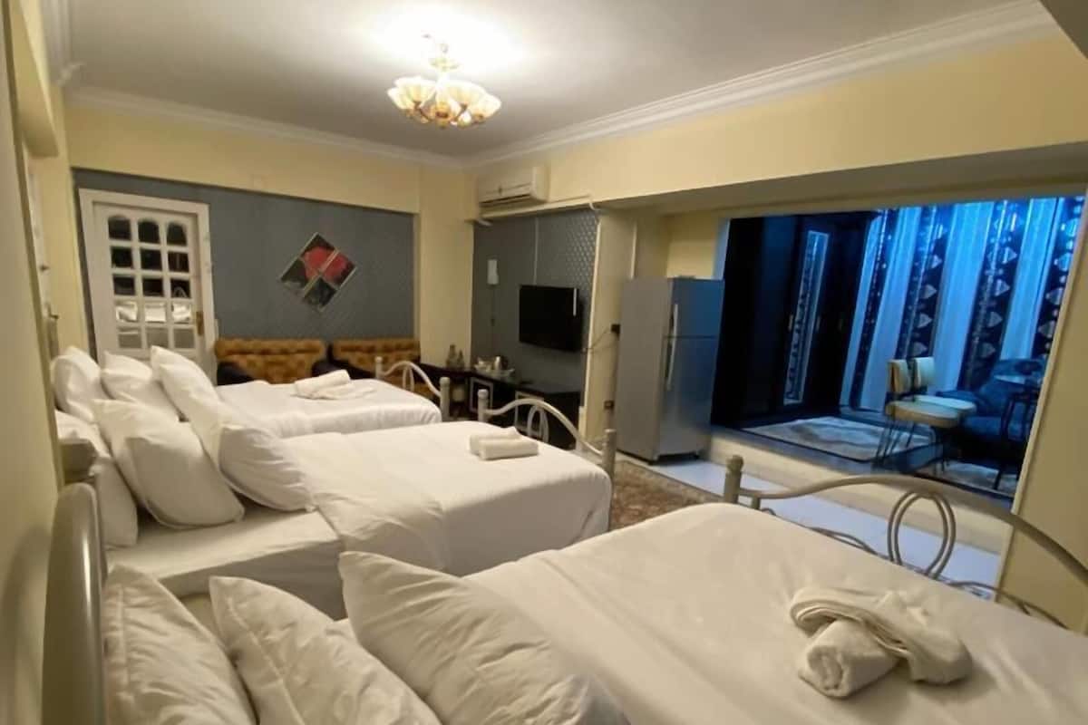 A hotel room with two beds, a television, and a view of the outside.