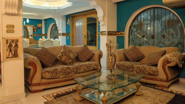 A living room with two sofas, a glass coffee table, and decorative items. -  Pyramita Hotel (Giza)