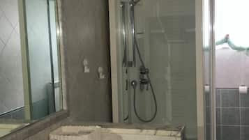 Een douche, een bidet, handdoeken, toiletpapier