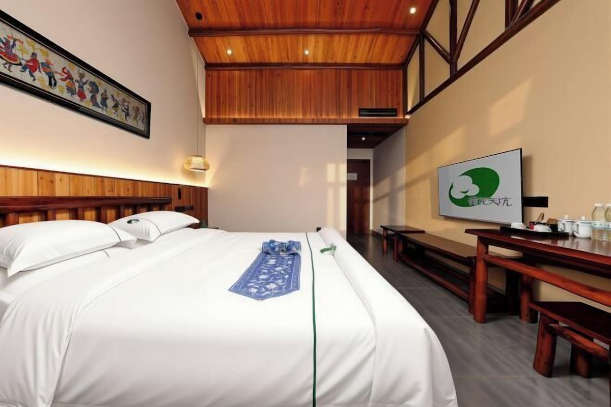 Une chambre d’hôtel avec un lit, un bureau et une télévision.