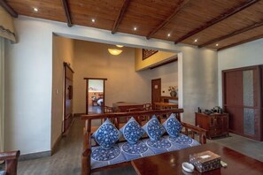 Un comedor de madera con una mesa, sillas y un banco con cojines estampados.