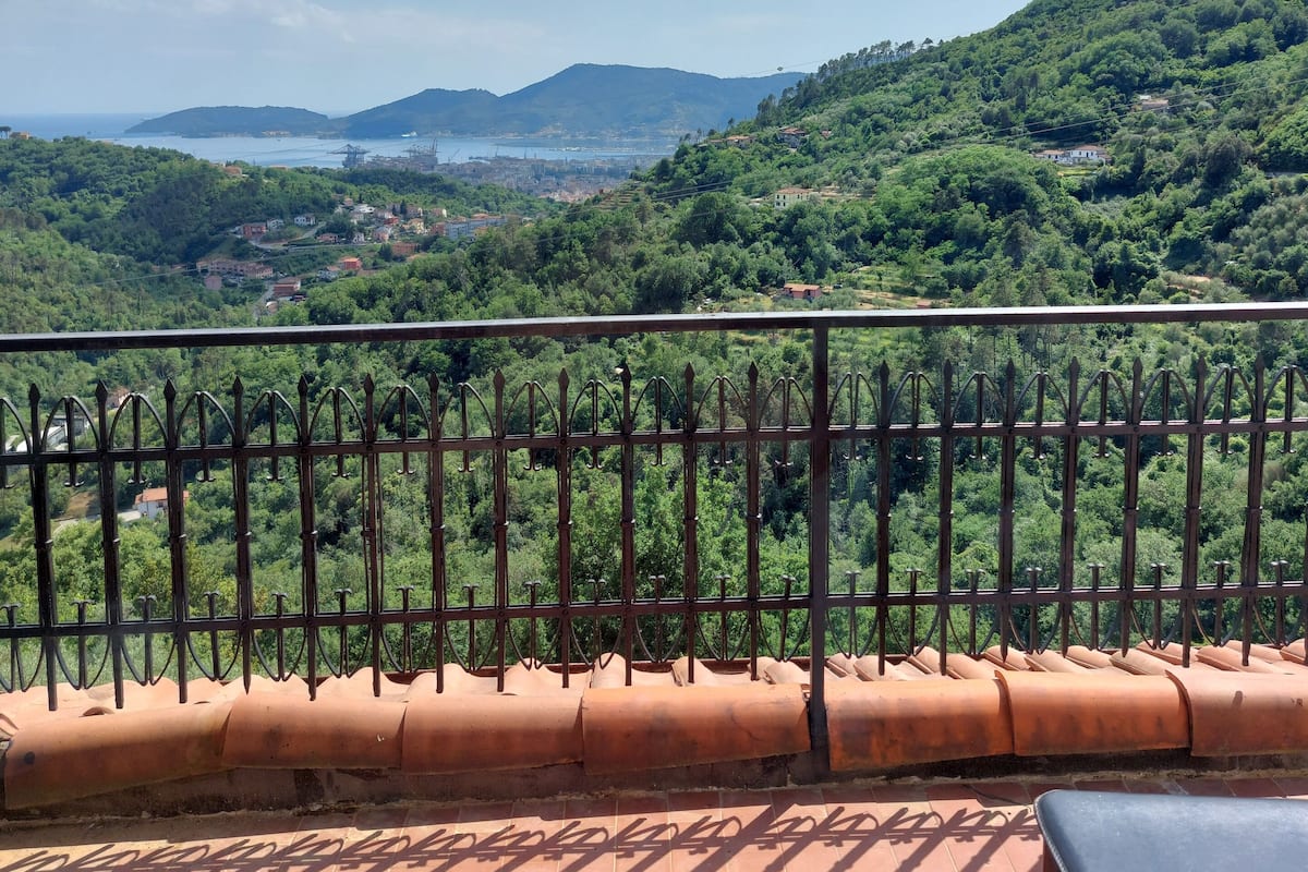 A terrace with a view of a green valley and distant mountains.