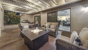 An outdoor patio with a fire feature, wicker furniture, and a view into the house.