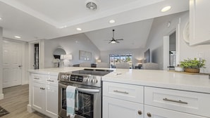 A modern kitchen with white cabinetry, a built-in oven, and a central island.