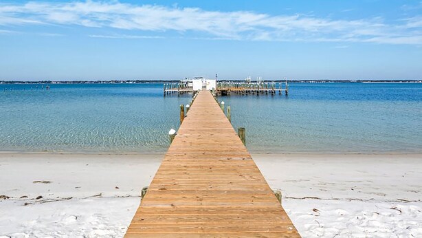 A wooden pier extending into calm waters with a clear sky. - When the Sun Goes Down 🌅 Navarre Retreat w/Golf Cart, Boat Slip + Pet Friendly (Navarre)