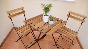 A wooden table with two chairs, a potted plant, and a white pot on the table. - Center, 2 min.de the beach, with terrace, air conditioning and heating. (Nerja)