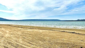 Una playa con vista despejada al agua y colinas lejanas.