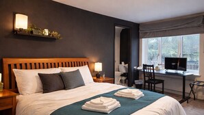 Une chambre d’hôtel avec un grand lit, des tables de chevet, un bureau avec une chaise, une fenêtre et un téléviseur.