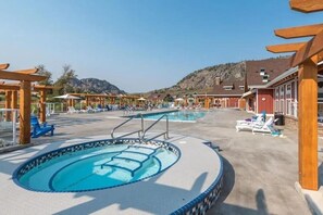 A pool area with multiple pools, sun loungers, and wooden pergolas.