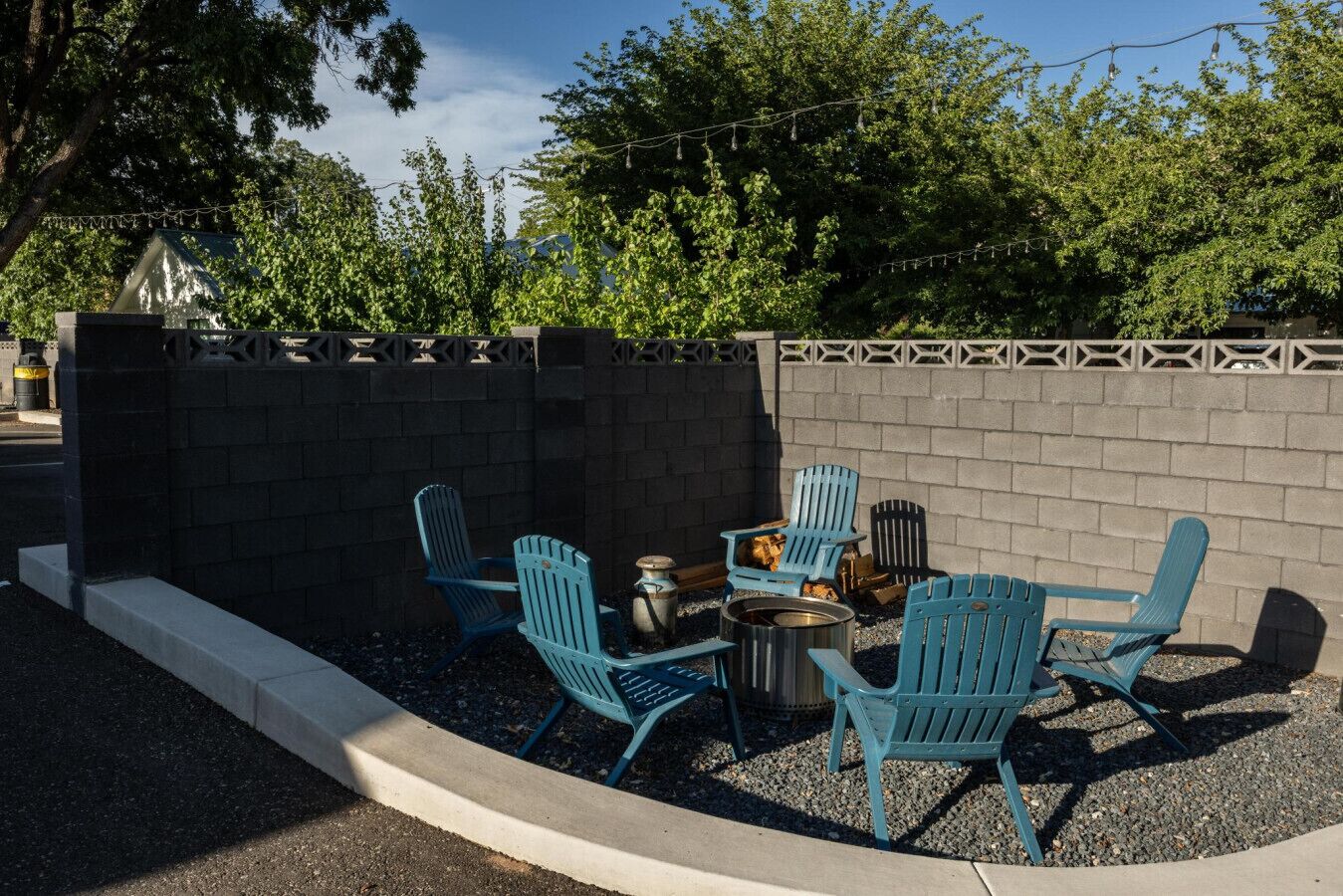 Un espacio al aire libre con sillas Adirondack azules y un brasero.