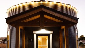 Un petit bâtiment circulaire avec une porte noire et un paillasson accueillant sur lequel est écrit « OH, BONJOUR ».