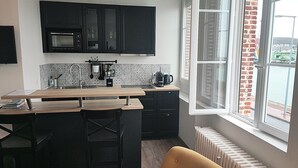 A modern kitchen with a central island, black cabinets, a microwave, and a coffee machine. - Elegant Studio, facing marina and harbour (Fécamp)