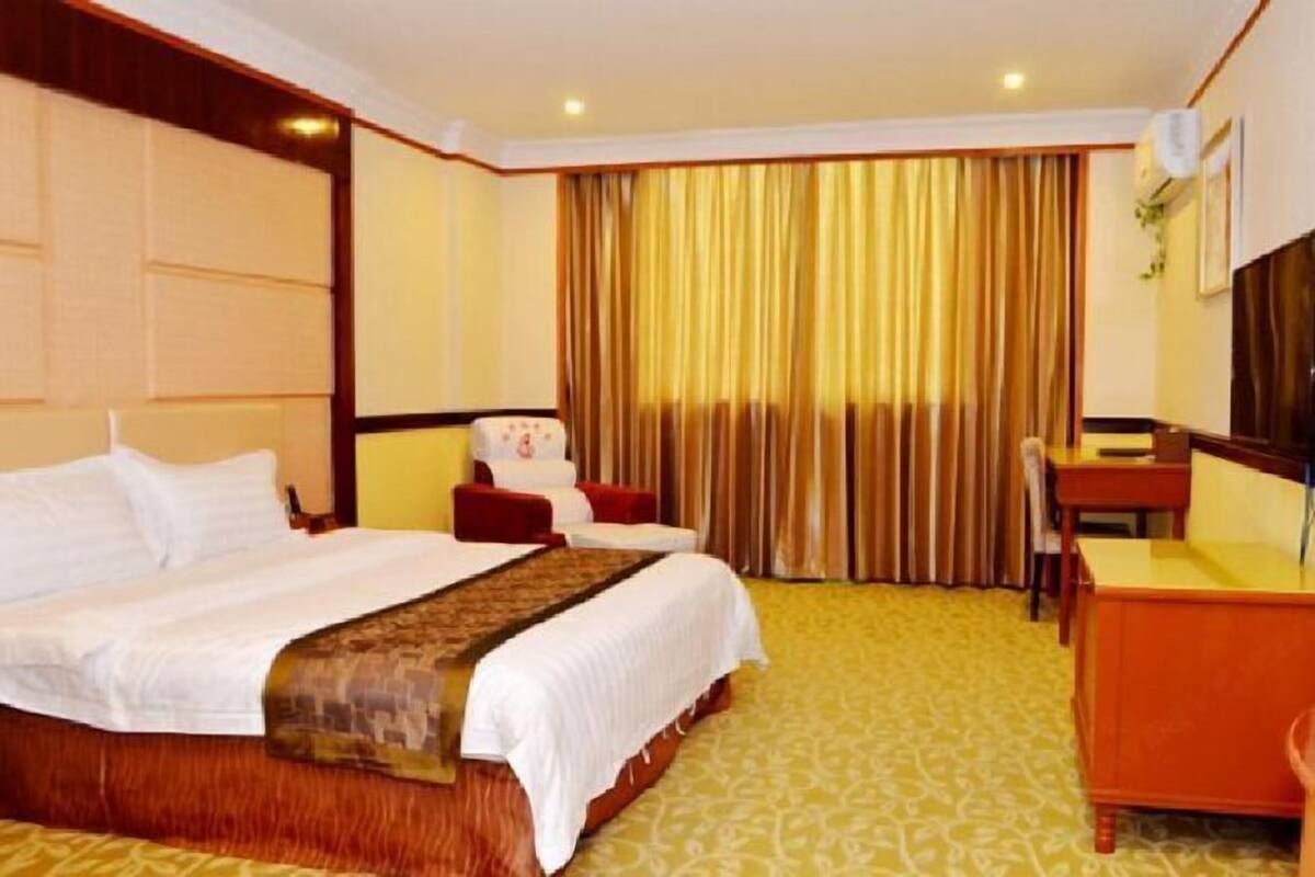 Een hotelkamer met een groot bed, een bureau en een stoel.