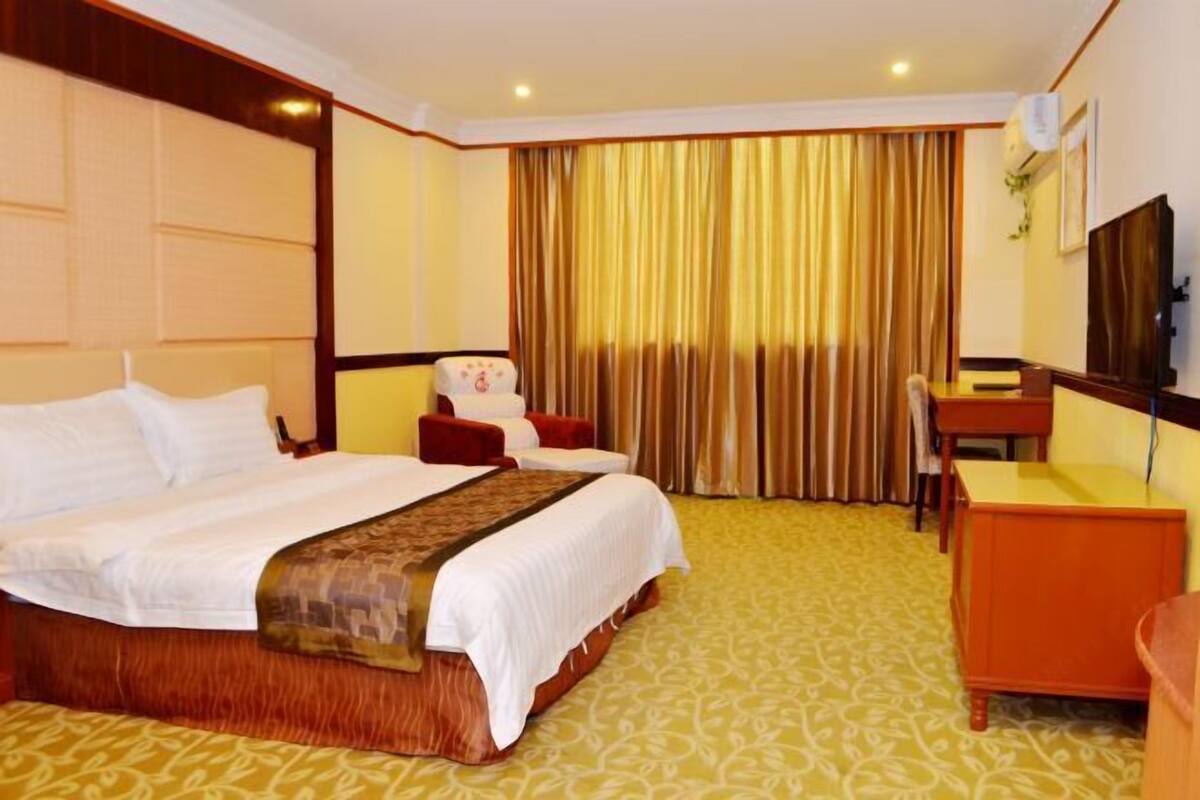 Een hotelkamer met een groot bed, een bureau, een stoel en een televisie.