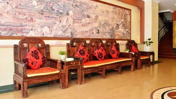 A traditional wooden bench with red cushions, a large mural on the wall, and a staircase in the background. - Peigen Yizutang Hotel (Huizhou)