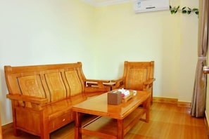 Um conjunto de sofá e poltrona de madeira em um quarto com uma mesa de madeira, uma pequena caixa e um estojo de lenços.